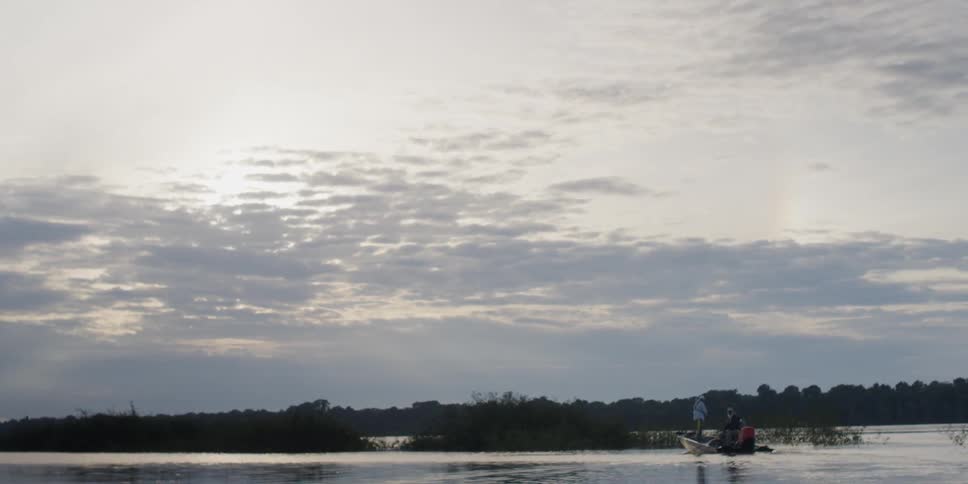 Two people ride in a small boat on a cloudy day