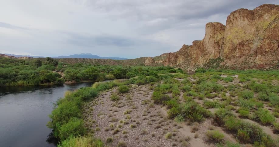 A river is winding its way through a desert landscape on a cloudy day