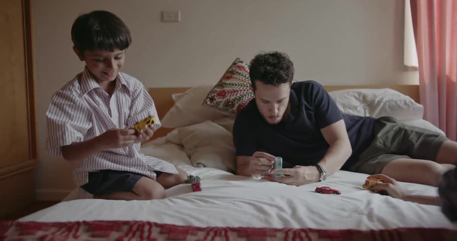 Man and woman sit on bed playing with their son