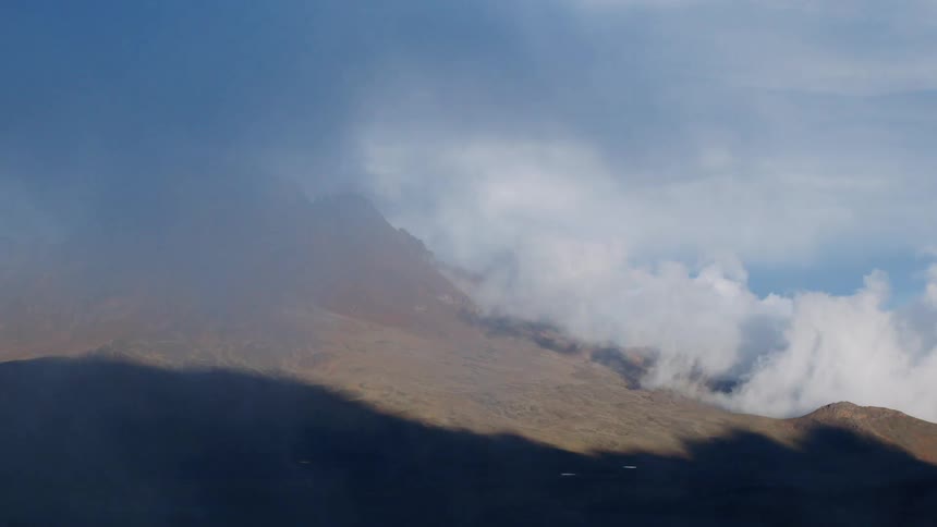 Clouds roll low over rocky mountains
