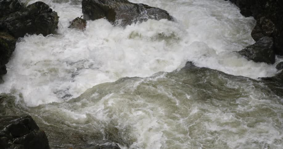 The stream pours down crashing on the rocks