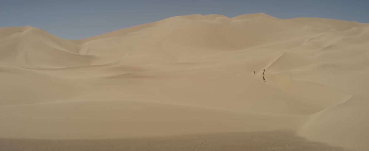 People are hiking down the dunes in the desert