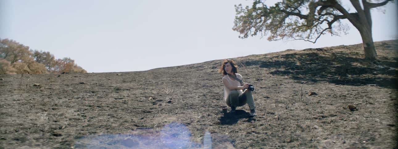 A photographer crouches in a rural field