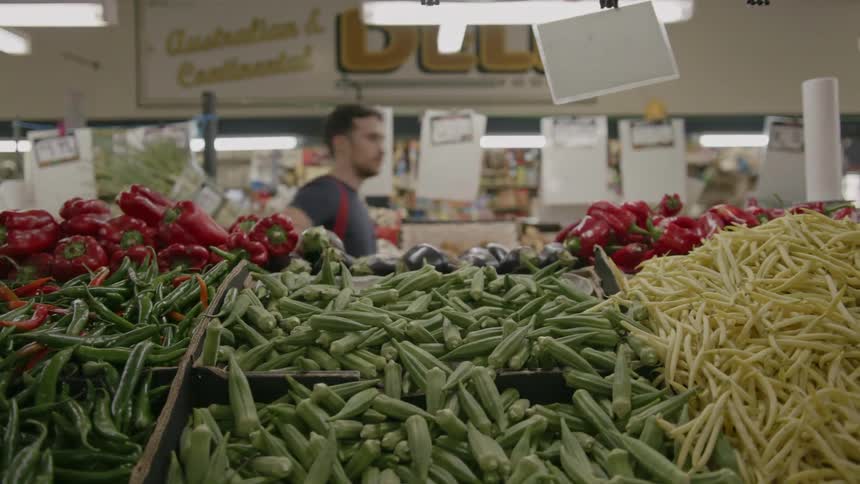 A man is browsing the vegetables in a grocery store