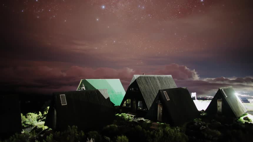 Clouds roll low behind several houses and lights shine brightly