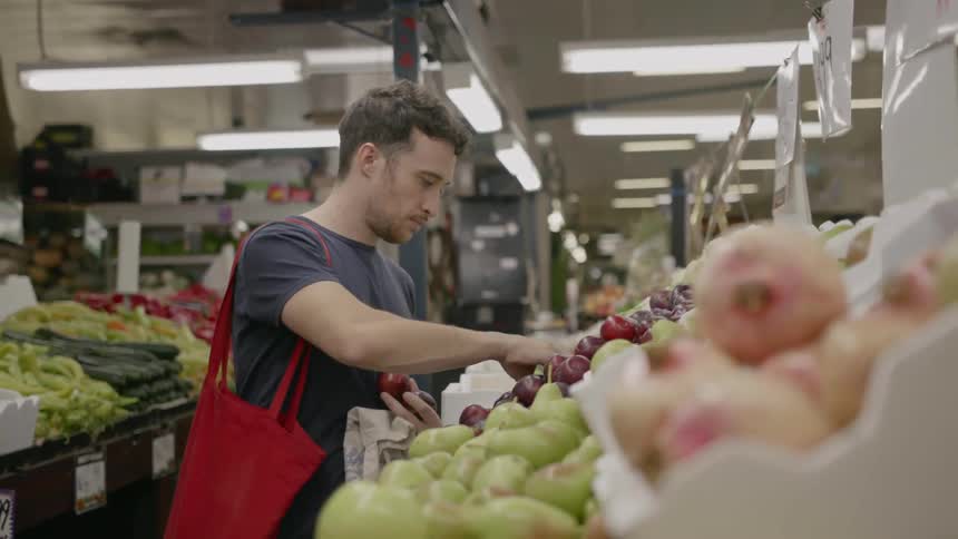 A man shops for produce in a grocery store