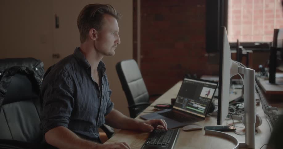 Man is sitting at desk and typing on computer keyboard