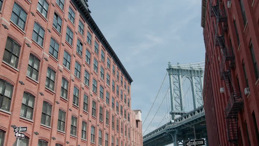 A bridge is looming over old buildings in a city on a sunny day