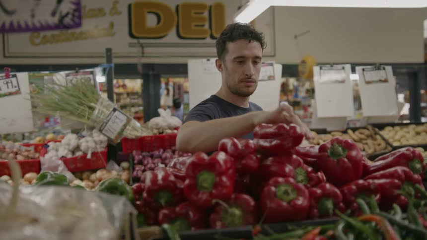 A man shops for red peppers at a market