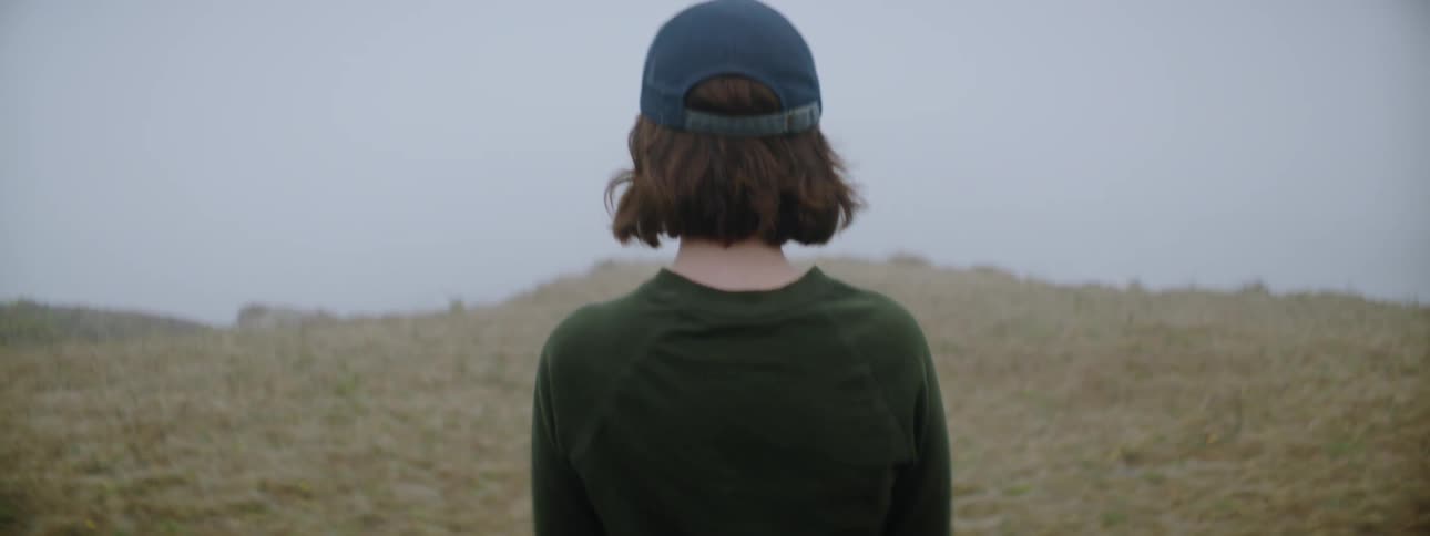 A woman looks out at nature from atop a cliff