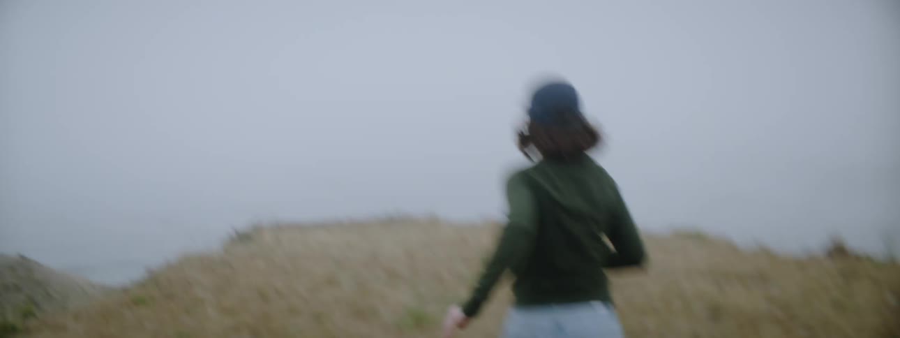 A woman is running up the hill towards the cliff