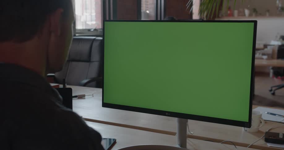 A man looks at a computer monitor