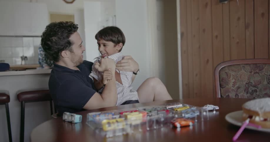 A father and son play at a dining table