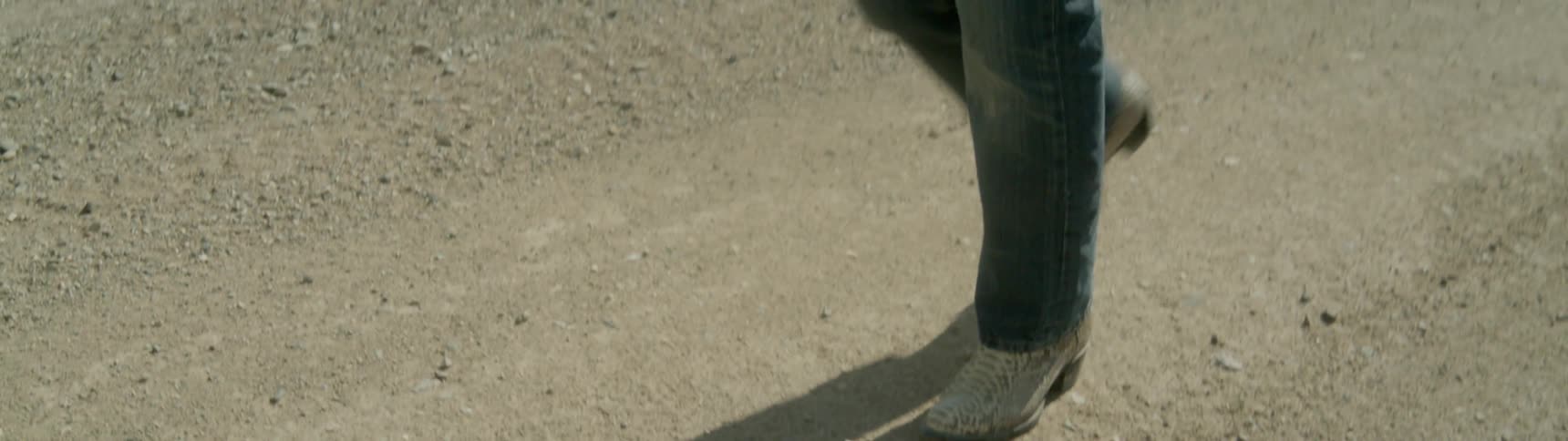 A person stumbles while walking outside under the sun