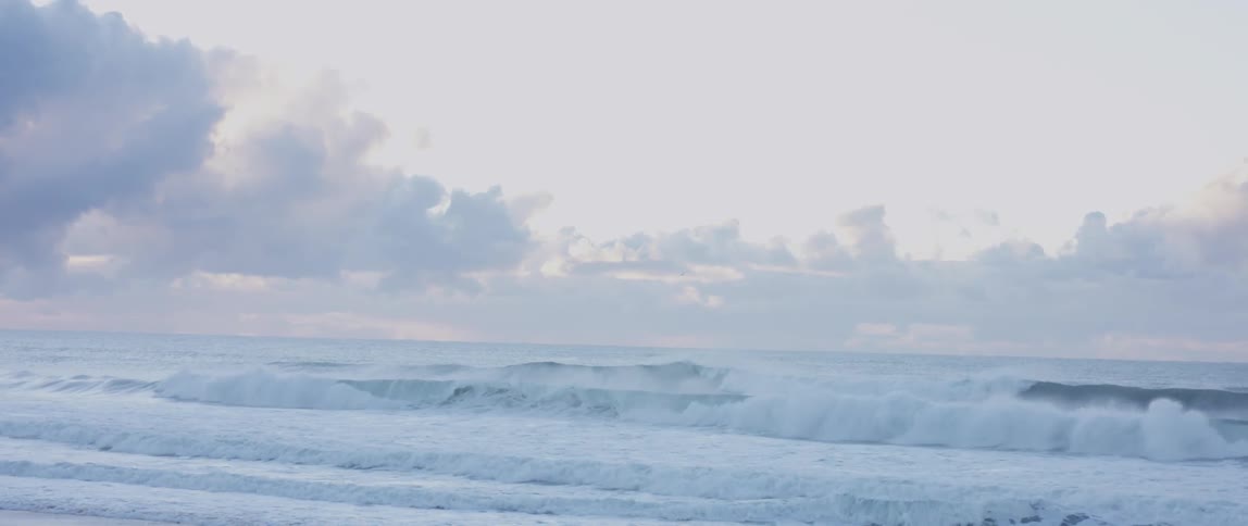 Large ocean waves roll into a beach
