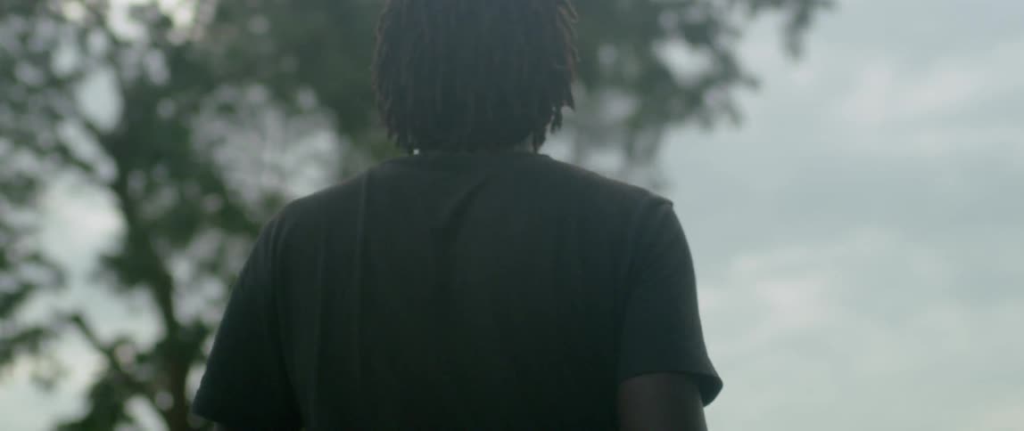 A man walks outside under a tree