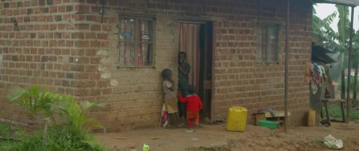 Children stand outside of a brick shack