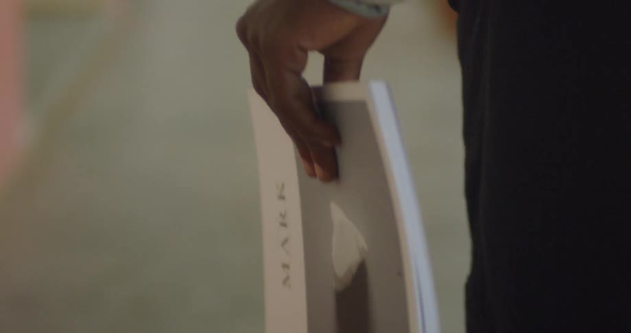 A man holds a book in his hand as he walks