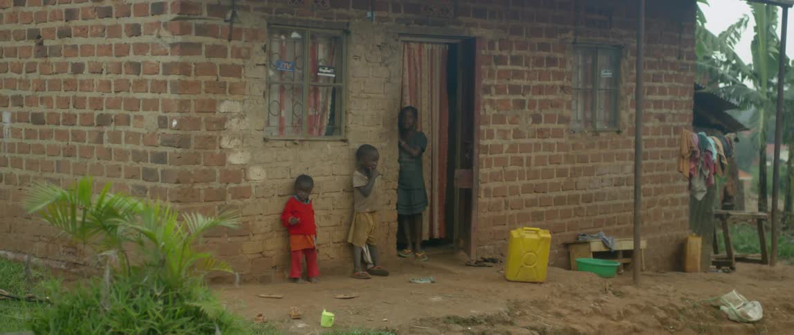Three children stand next to a home