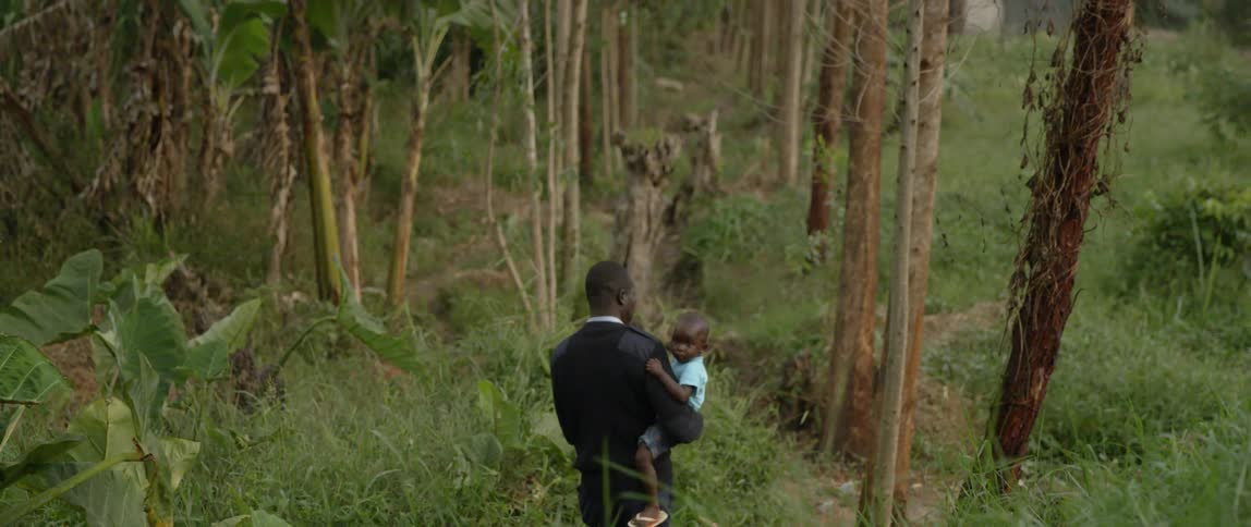 A man carries a young boy in a forest