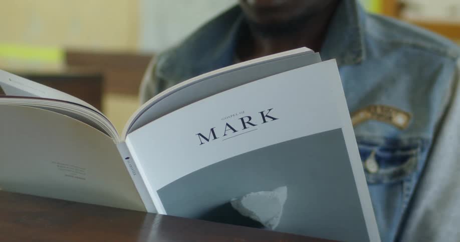 A man reads from a book at a table