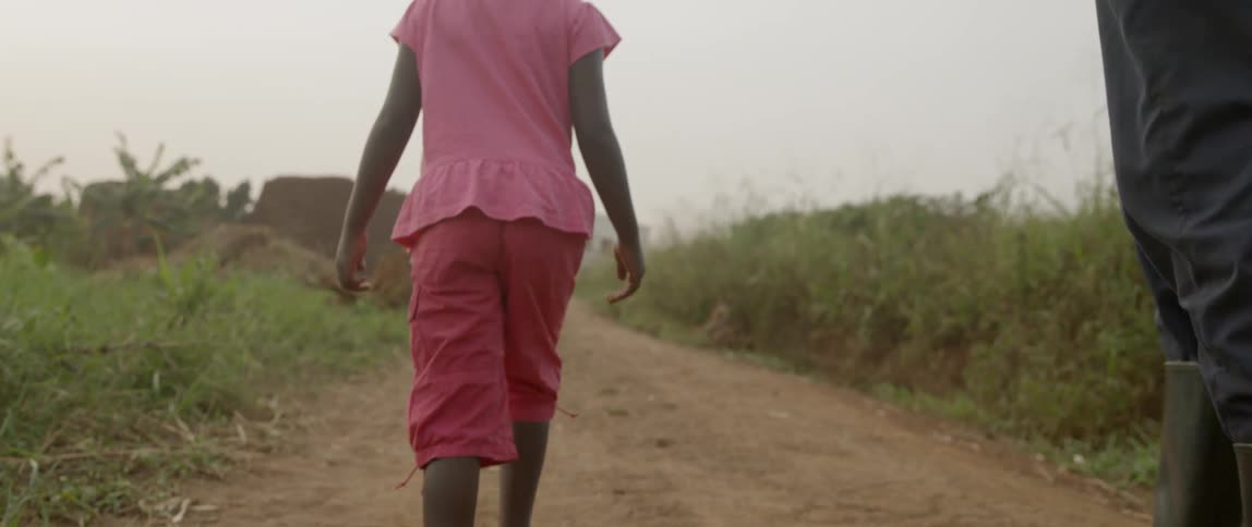 A young girl walks on a dirt path in flip flops