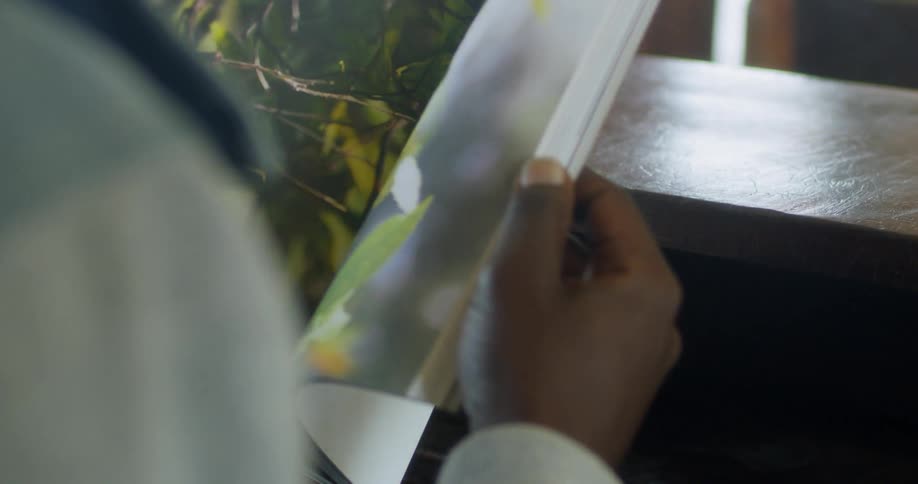 A person is flipping through a book by a desk