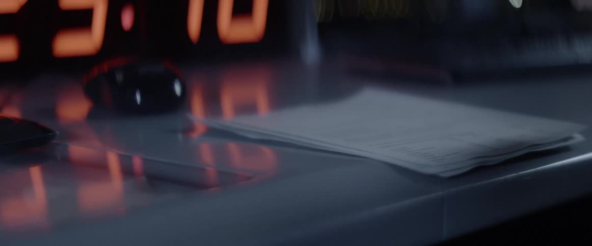 Papers fall onto a desk near a large clock