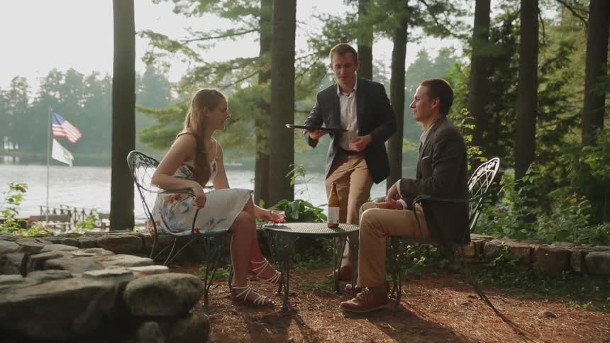 A man and woman are served alcohol outside