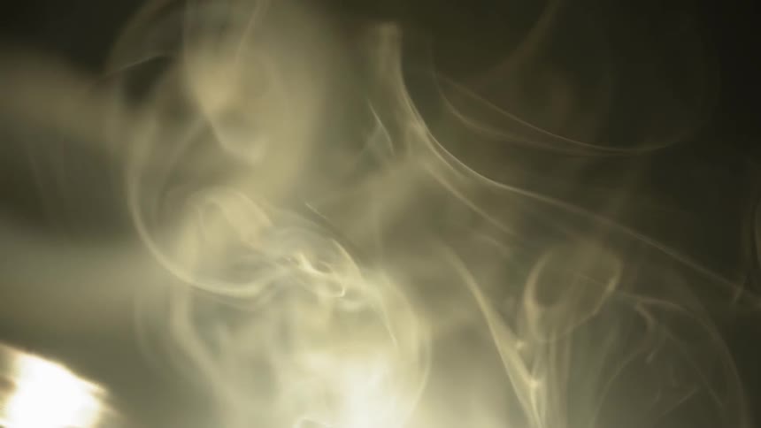 Smoke billows with a light shining behind it
