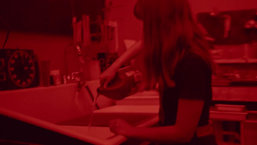 A woman develops film in a darkroom