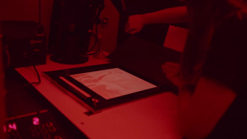 A woman pushes buttons in a darkroom