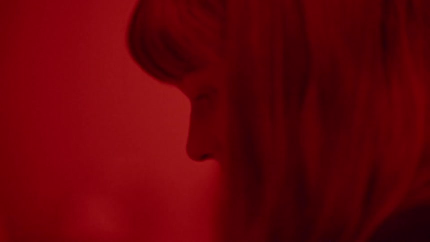 Woman illuminated by red light looks down