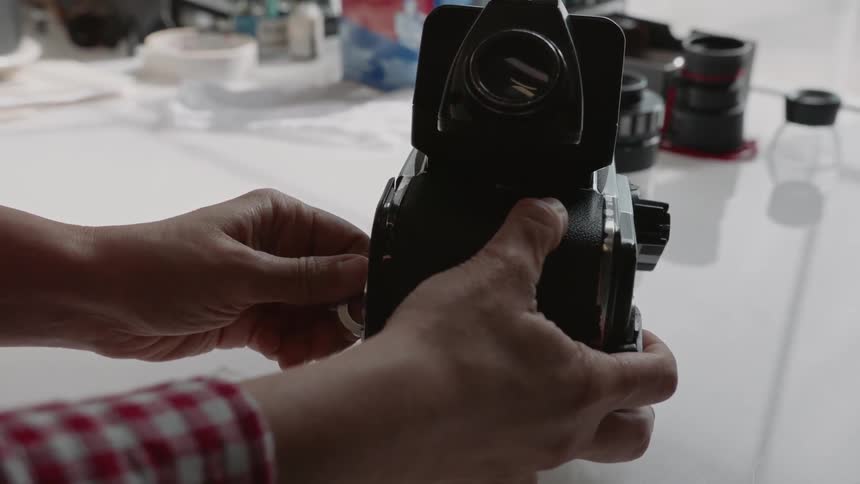 A person is putting the film roller back into a medium format camera inside in daylight