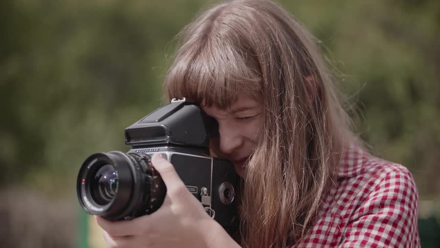 A woman uses a camera outside on a sunny day