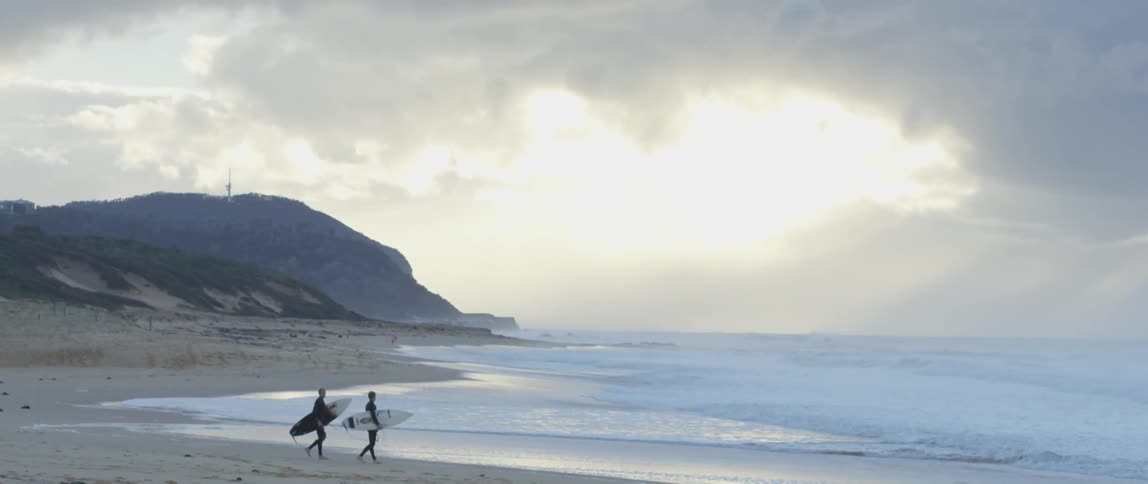 Surfers walk along the beach