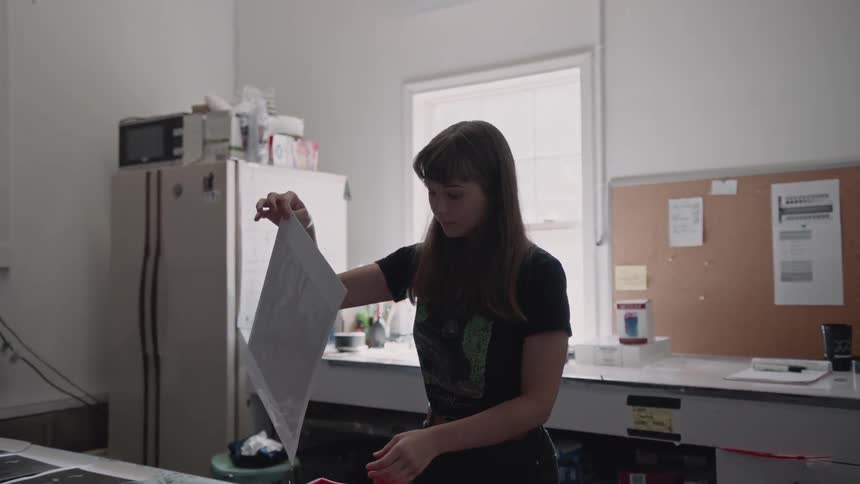 Woman picks up a picture out of a red tray and looks at it