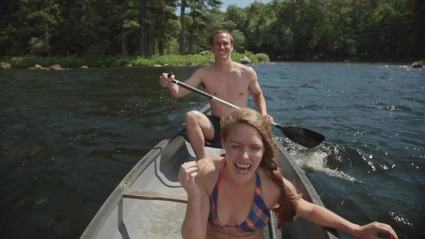 A man and woman paddle in a kayak on a lake