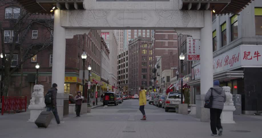 People walk through an entry arch into a city