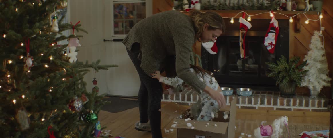 A mother is lifting her daughter out of a box containing shipping peanuts on christmas