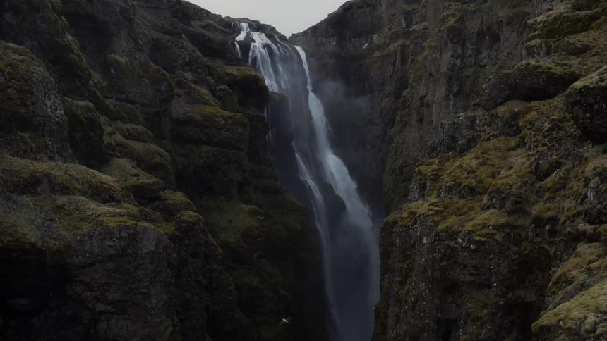 Waterfall flowing down a mossy rock cliff