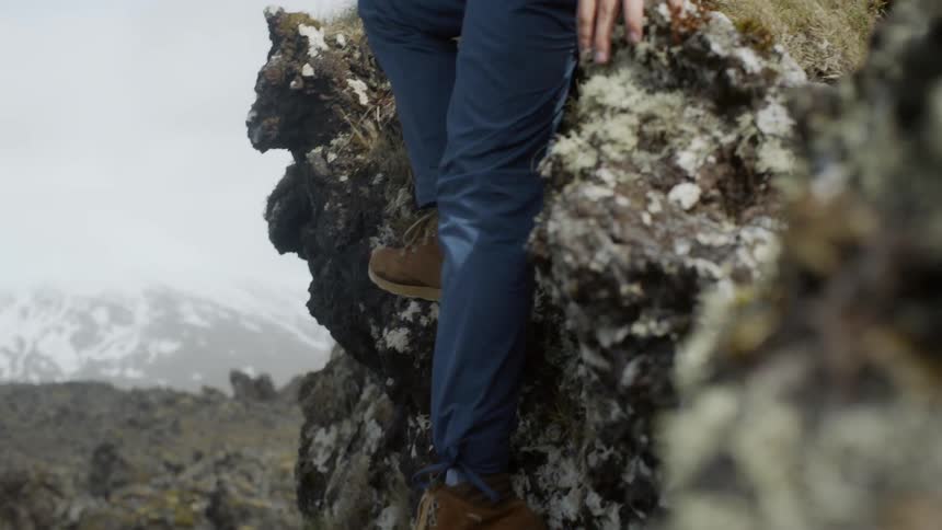 Woman climbs down from a large rock