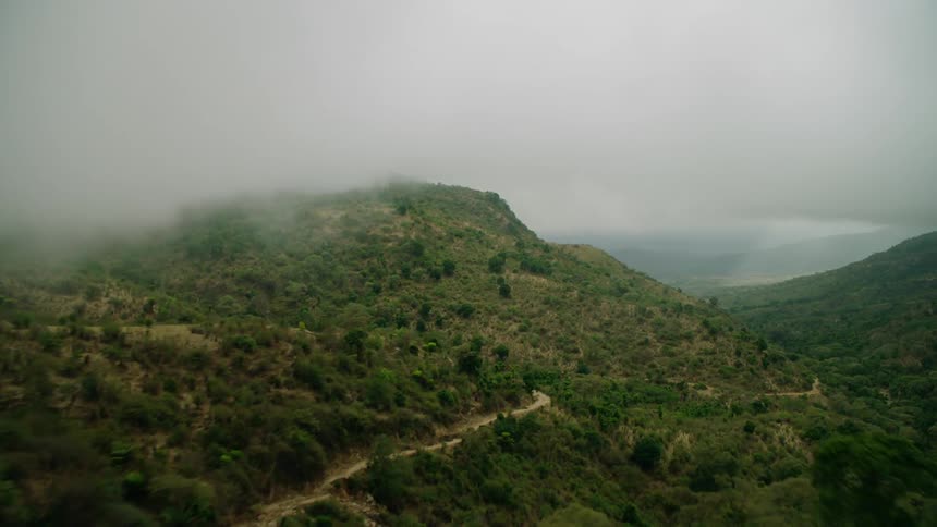 Clouds covering green mountains