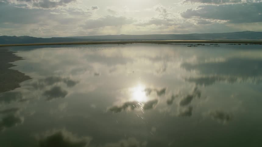 The clouds and sun are reflected off the water