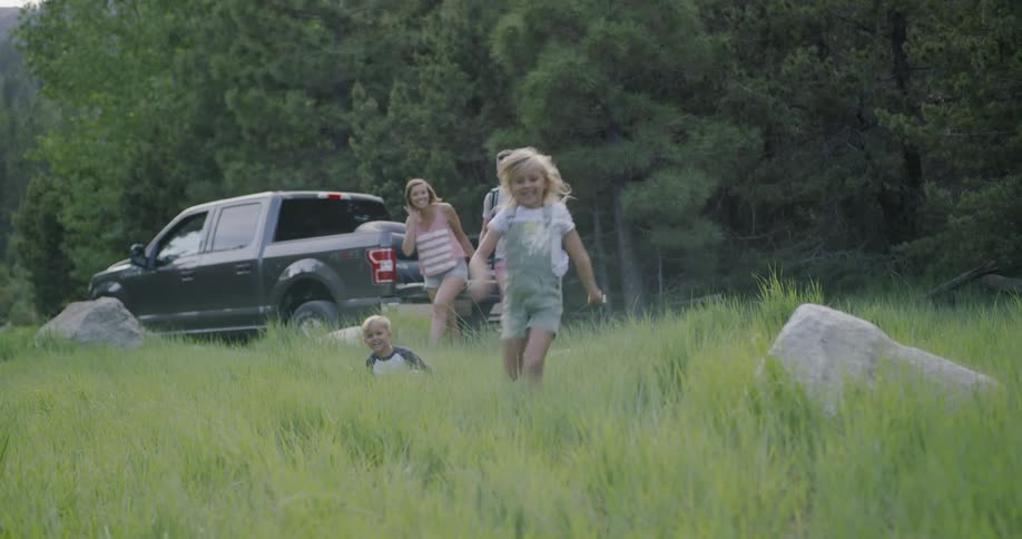 A family walks away from their truck into a grassy field