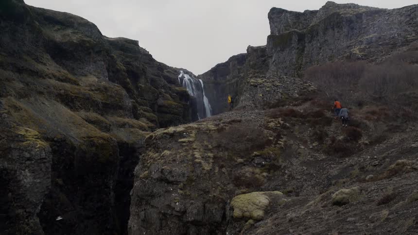 People hack towards a cliff and waterfall