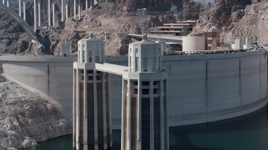 Vehicles are crossing over a dam in daylight