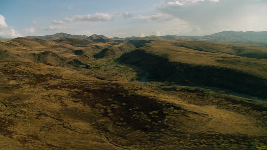 Hilly brown landscape with clouds overhead