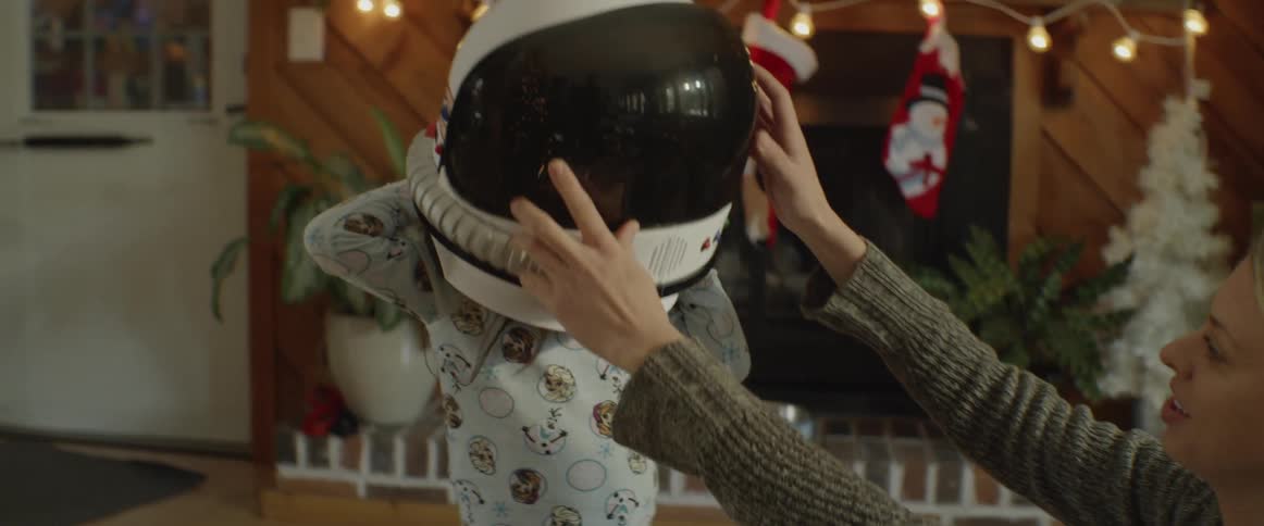 Little girl trying on toy astronaut helmet on christmas