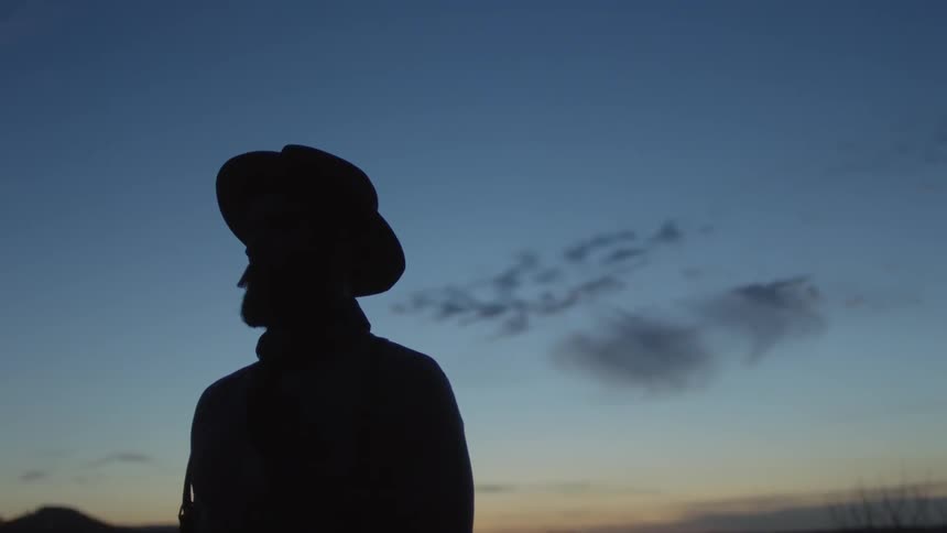 A man is standing in the shadow of the dawn sky